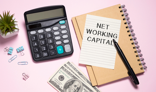 Net Working Capital text on notepad with keyboard on table.