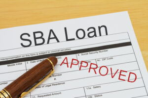  SBA Loan application form with a pen on a desk with an approved stamp