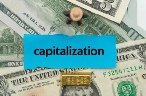 capitalization written on a slip of paper with dollar bill background