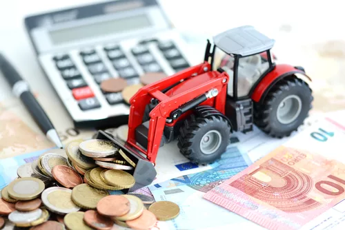 Analyzing financial result in agriculture with tractor pushing a lot of money near office tools heavy equipment loan